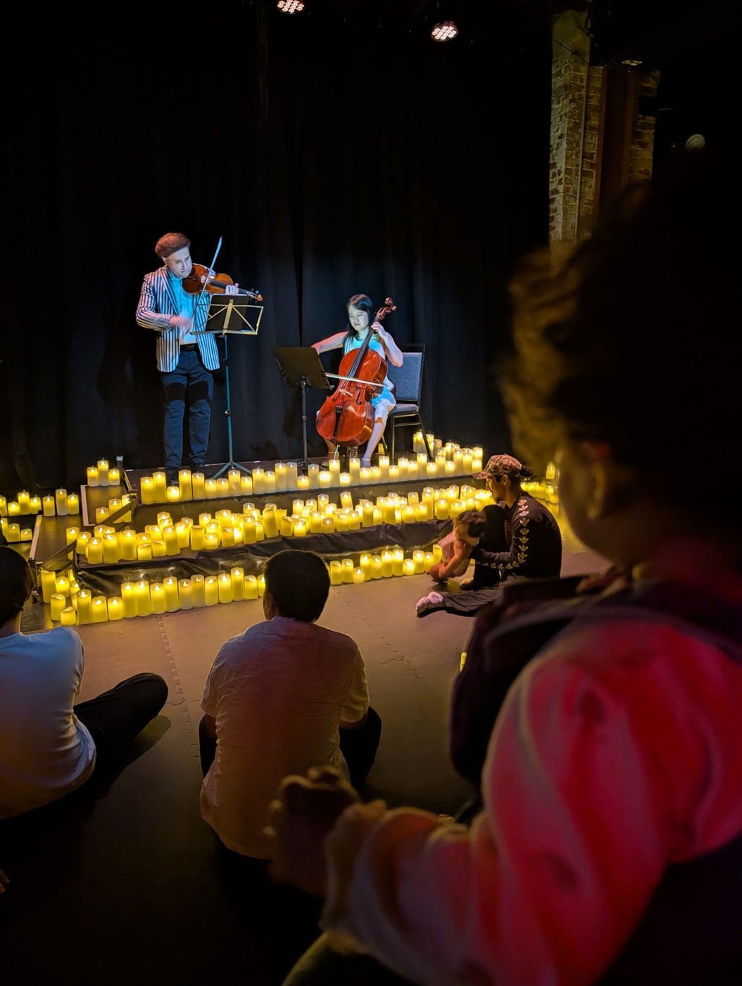 A candlelit chamber concert with a young child in the audience